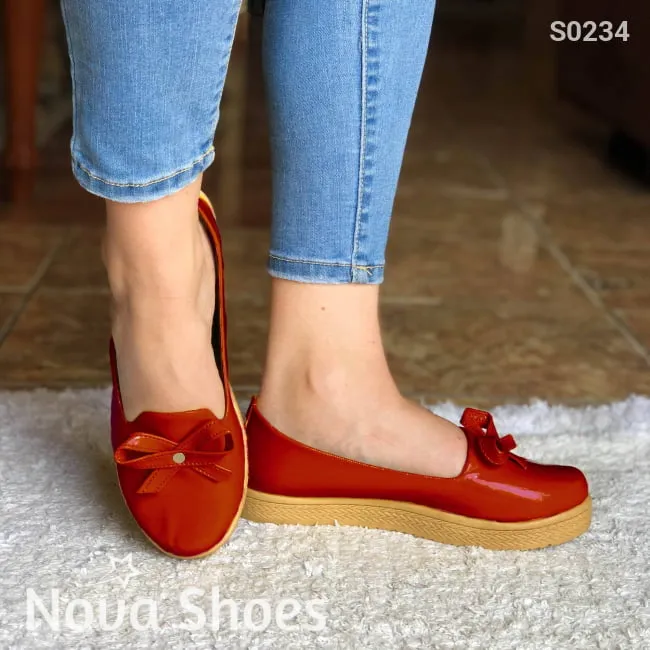 Zapatos bajos hechos en charol, decorados con un chongo