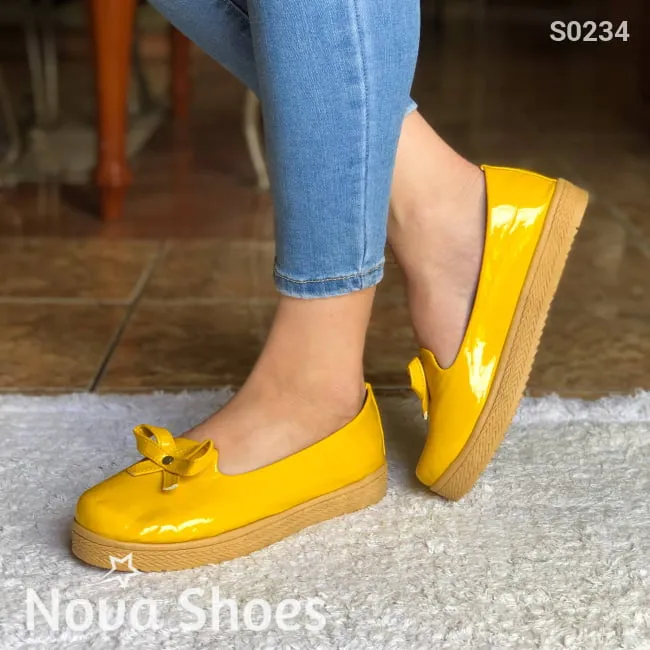 Zapatos bajos hechos en charol, decorados con un chongo