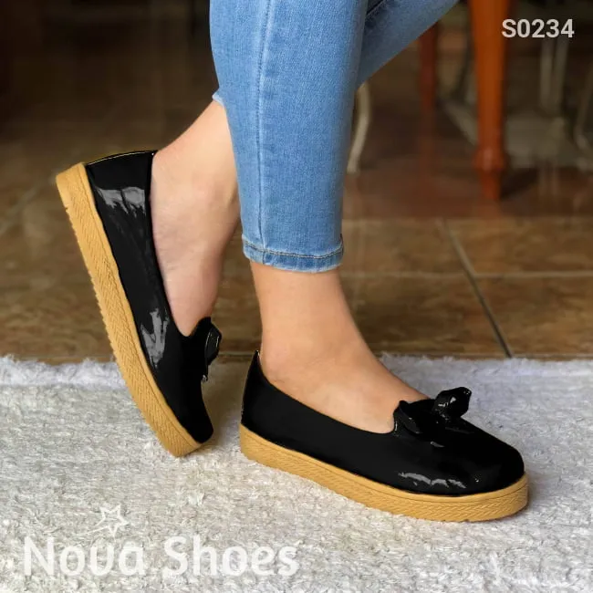Zapatos bajos hechos en charol, decorados con un chongo