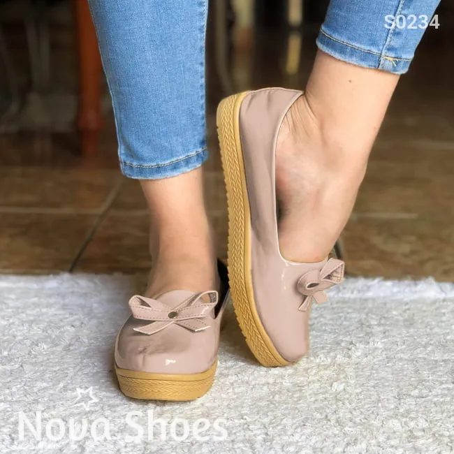 Zapatos bajos hechos en charol, decorados con un chongo