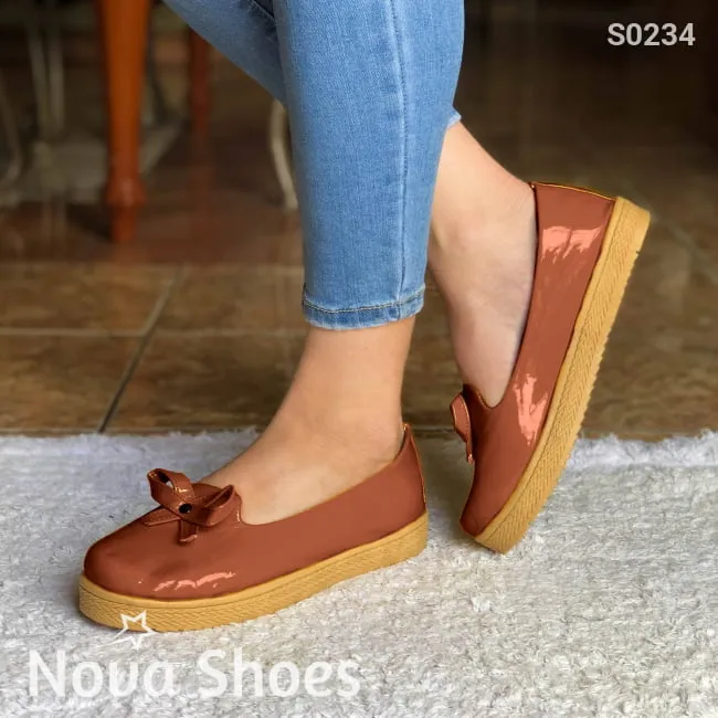 Zapatos bajos hechos en charol, decorados con un chongo